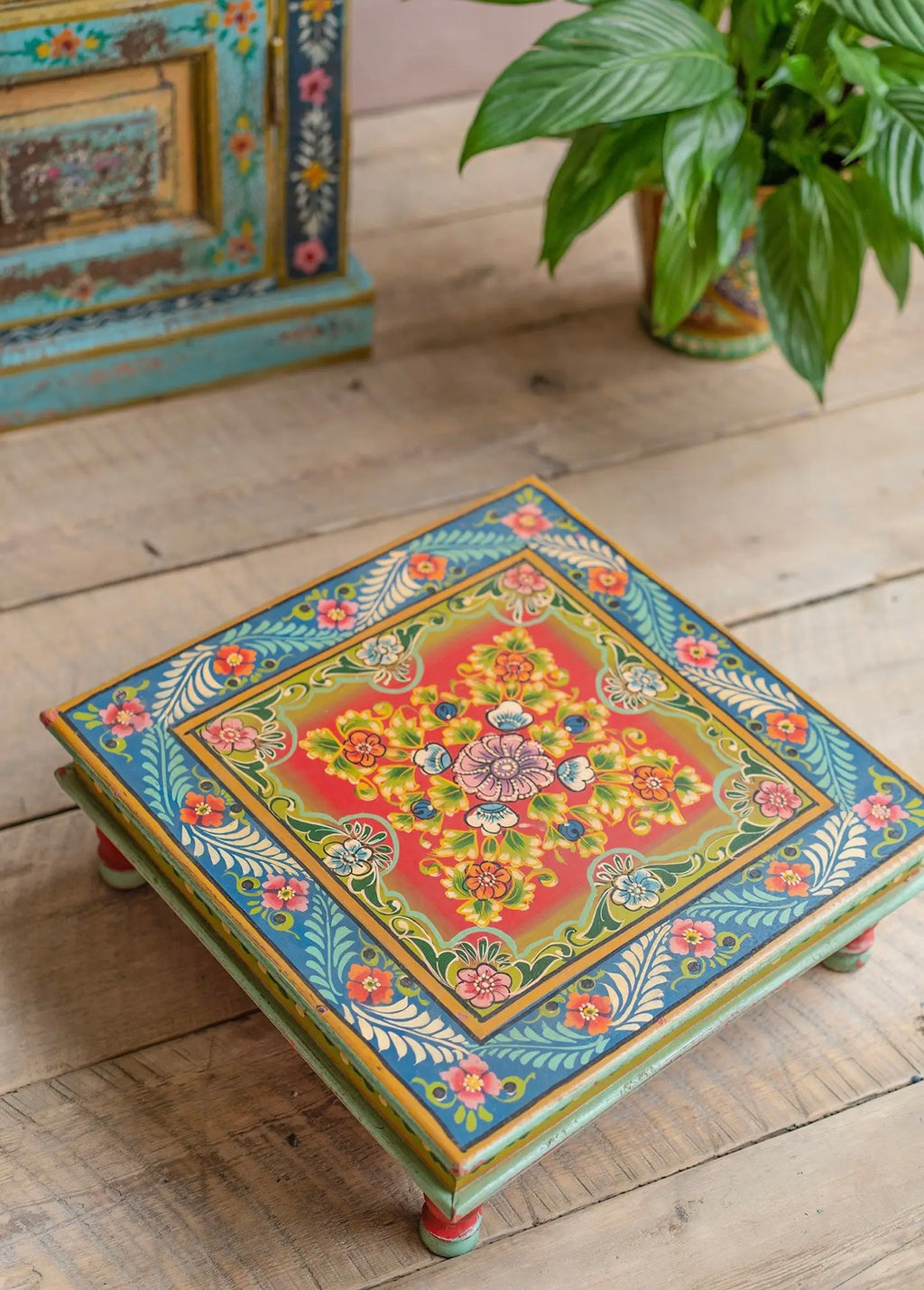 Top view of a hand-painted square floral chowki table with blue border and red centre