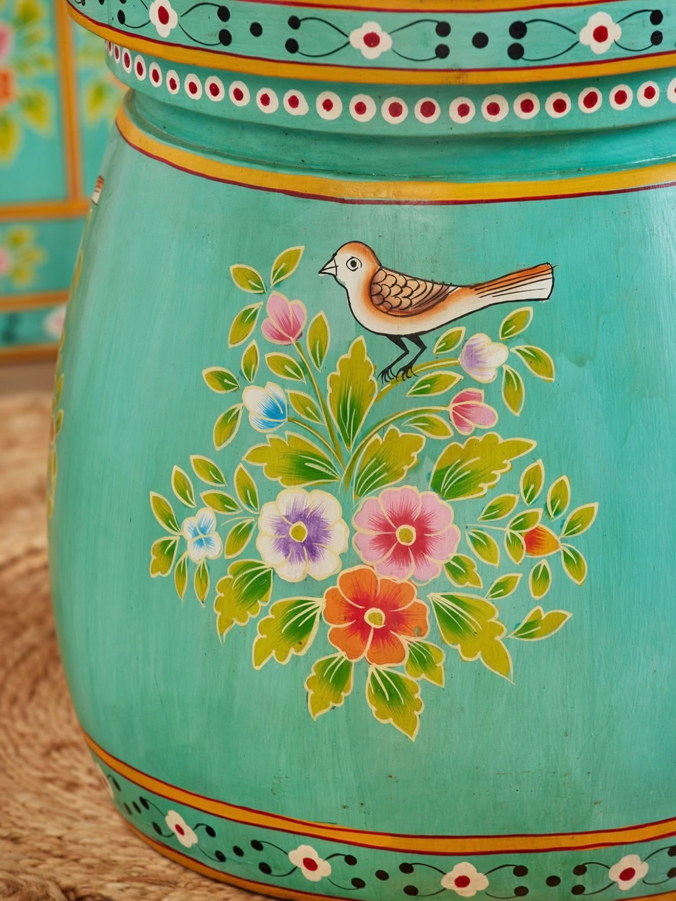 Close-up of hand-painted bird and colourful floral motif on turquoise accent table